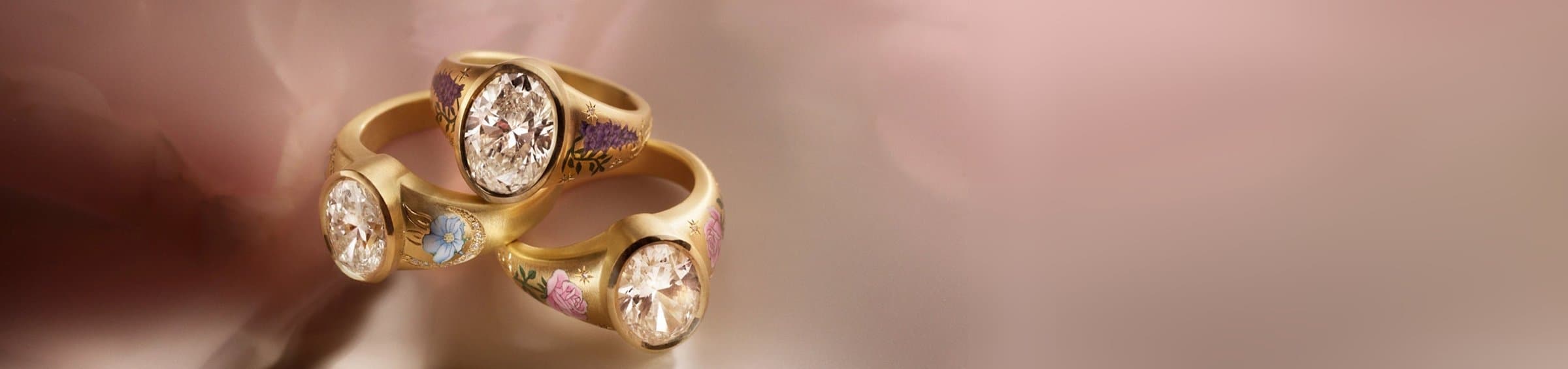 Three Cece hand-enamelled gold diamond rings on soft pink silk